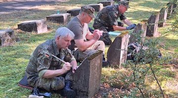 Menschen in Uniform reinigen Grabsteine